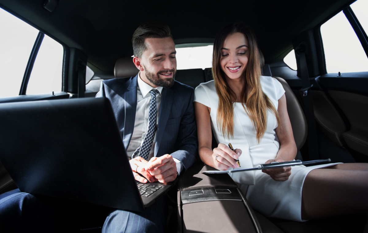 man and woman discussing work documents in limo